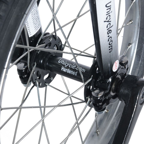 Närbild på svart nav märkt "Unicycle.com Hardened" och svart gaffel på en enhjuling. Visar nav, ekrar och vevarmens fäste