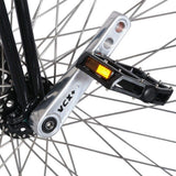 Närbild på den polerade Nimbus VCX Plus-vevarmen och svart pedal på höghjulingens framhjul, visar tydligt VCX+-märkningen