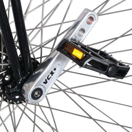 Närbild på den polerade Nimbus VCX Plus-vevarmen och svart pedal på höghjulingens framhjul, visar tydligt VCX+-märkningen