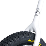 Närbild på den vita, smala enhjulingsgaffeln som går runt ett svart Maxxis-däck med grovt mönster. Visar navets logotyp